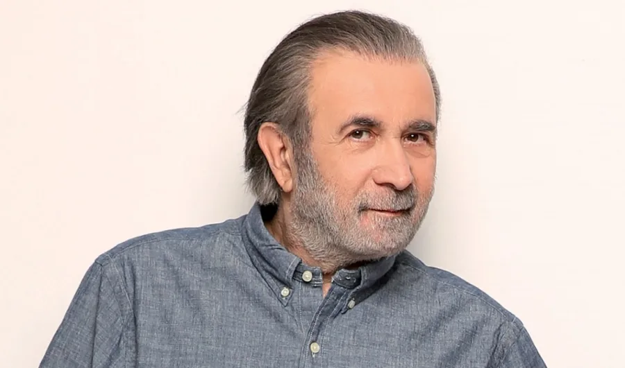 Ο Λάκης Λαζόπουλος με γκρίζα γένια και μπλε πουκάμισο.