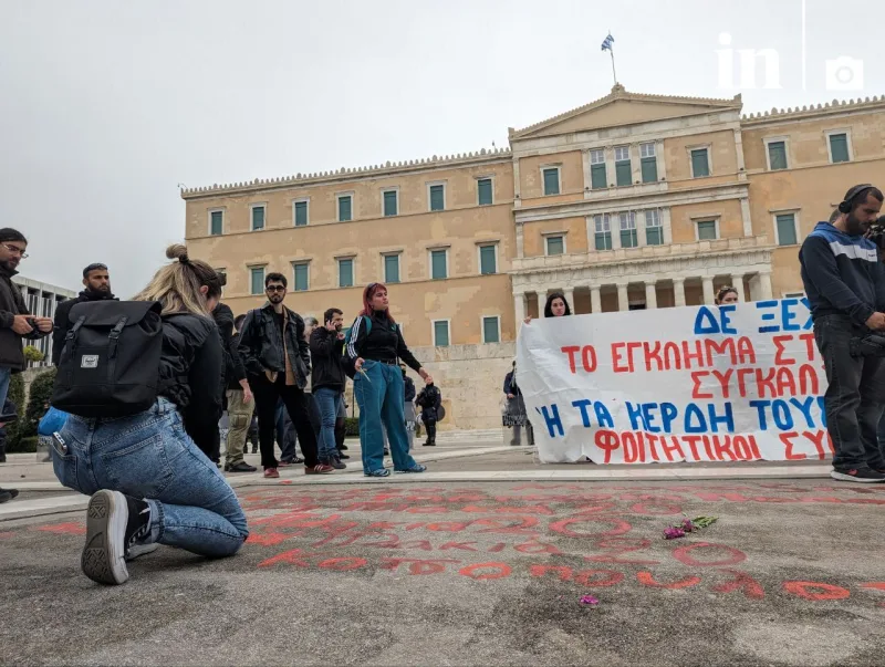 Φοιτητές έξω από τη Βουλή γράφουν ονόματα θυμάτων των Τεμπών στο έδαφος.