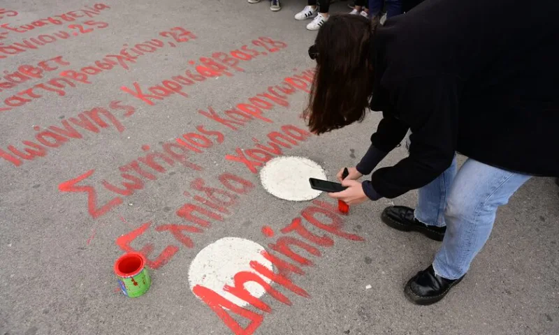 Άτομο γράφει με κόκκινη μπογιά ονόματα θυμάτων των Τεμπών στο Σύνταγμα.