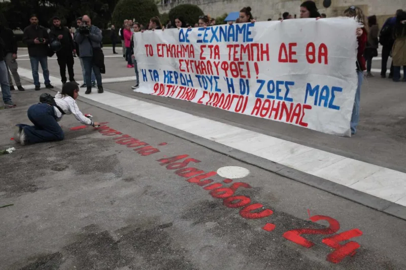 Φοιτητές γράφουν ονόματα θυμάτων των Τεμπών έξω από τη Βουλή.