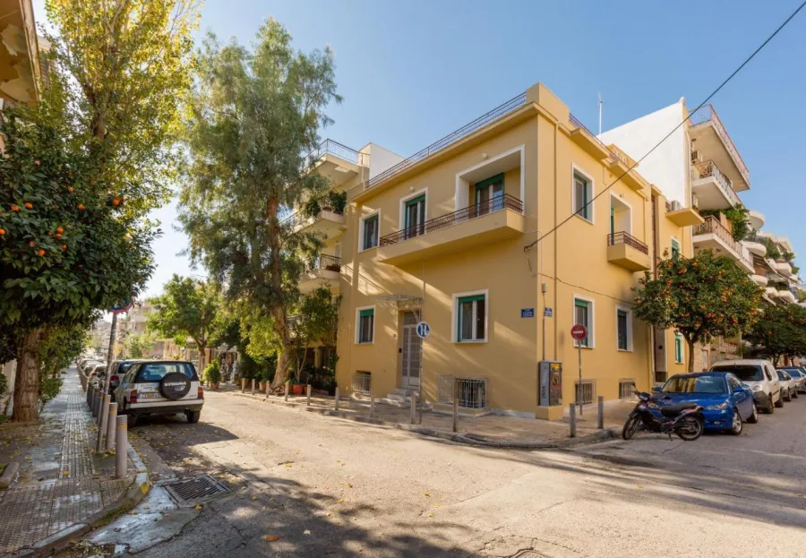 Άποψη δρόμου στην Αθήνα με νεοκλασικά κτίρια και δέντρα.