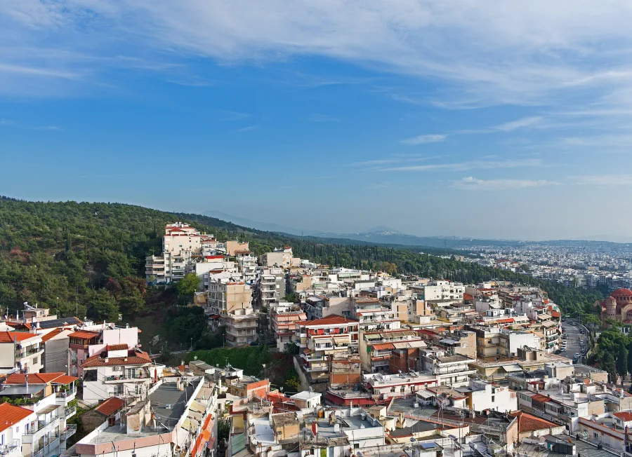Πανοραμική άποψη πυκνοκατοικημένης περιοχής στην Ελλάδα με λόφους στο βάθος.