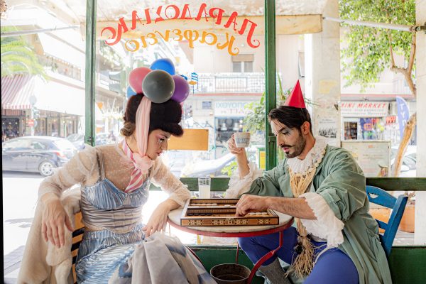 Δύο ηθοποιοί της ομάδας C for Circus με θεατρικά κοστούμια παίζουν τάβλι σε καφενείο.