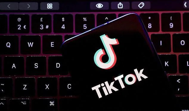 Το λογότυπο του TikTok σε οθόνη smartphone πάνω από πληκτρολόγιο laptop.