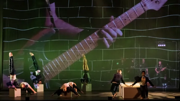 Σκηνή από την παράσταση The Wall - Pink Floyd's Rock Opera με ακροβάτες και προβολή κιθάρας.