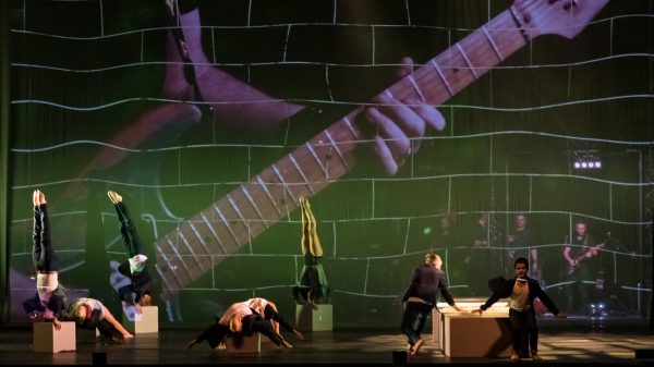 Σκηνή από την παράσταση The Wall - Pink Floyd's Rock Opera με ακροβάτες και προβολή κιθάρας.