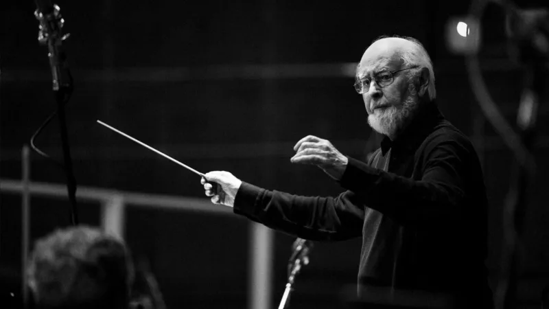 Ο John Williams διευθύνει ορχήστρα με μπαγκέτα.
