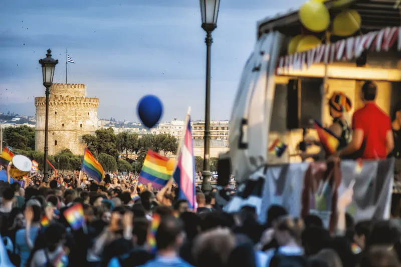 Πλήθος κόσμου με σημαίες Pride στη Θεσσαλονίκη με φόντο τον Λευκό Πύργο.