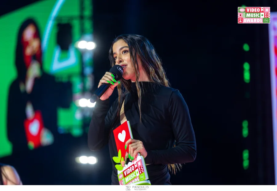 Τραγουδίστρια στη σκηνή των Mad VMA 2024 κρατώντας βραβείο και μικρόφωνο.