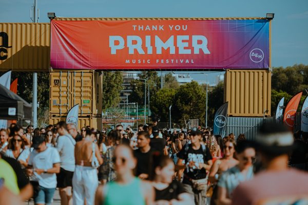 Πλήθος κόσμου στην είσοδο του Primer Music Festival κάτω από μια μεγάλη επιγραφή.