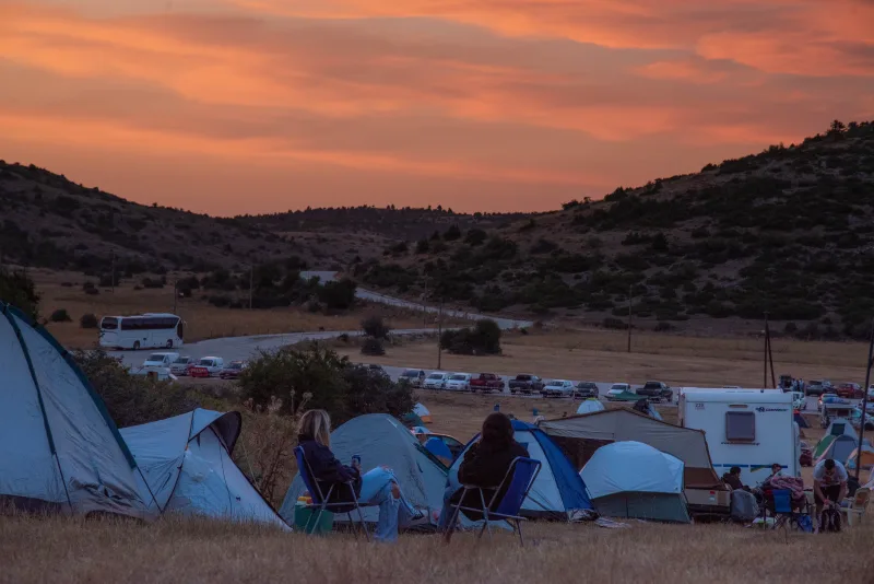 Σκηνές κάμπινγκ και κόσμος στο Voes Festival στο Χιονοδρομικό Κέντρο Ζήρειας κατά το ηλιοβασίλεμα.