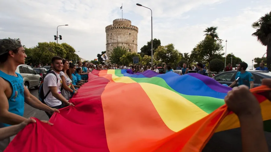 Πλήθος κόσμου κρατά μια τεράστια σημαία του Pride μπροστά από τον Λευκό Πύργο στη Θεσσαλονίκη.