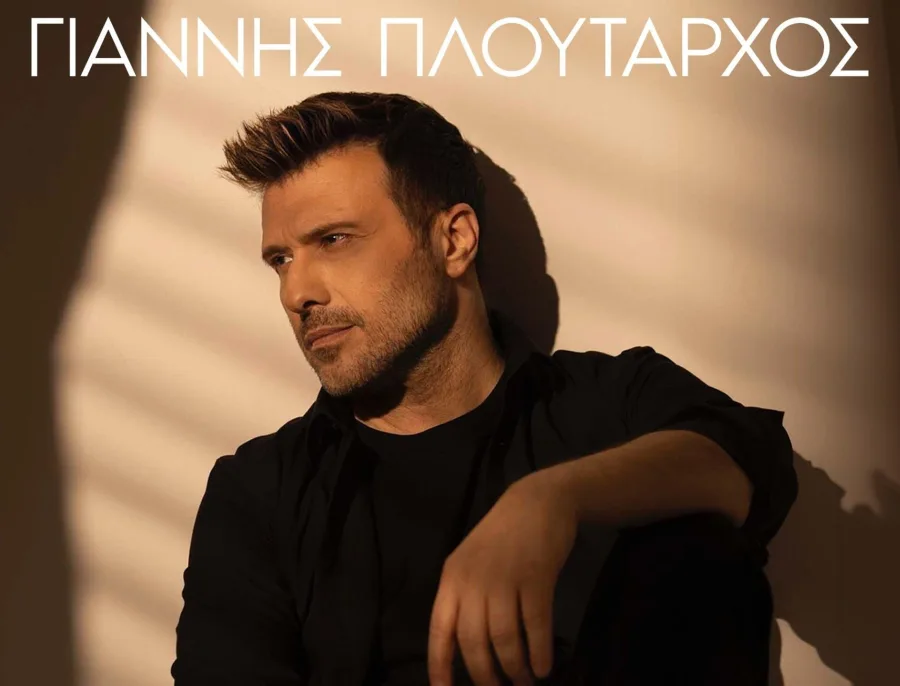 Ο Γιάννης Πλούταρχος σε κοντινό πλάνο με μαύρο πουκάμισο.