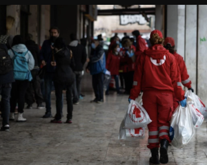Εθελοντές του Ελληνικού Ερυθρού Σταυρού με σακούλες ανθρωπιστικής βοήθειας σε δρόμο.
