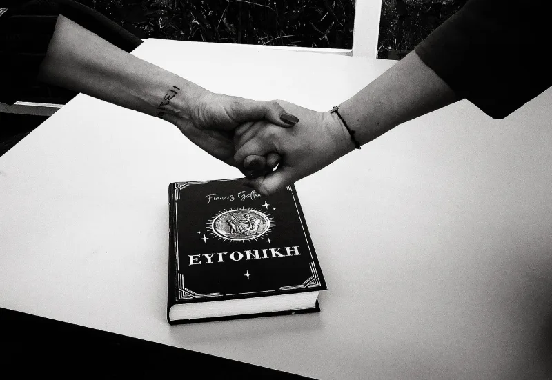Δύο χέρια πιασμένα πάνω από ένα βιβλίο με τίτλο ΕΥΓΟΝΙΚΗ.