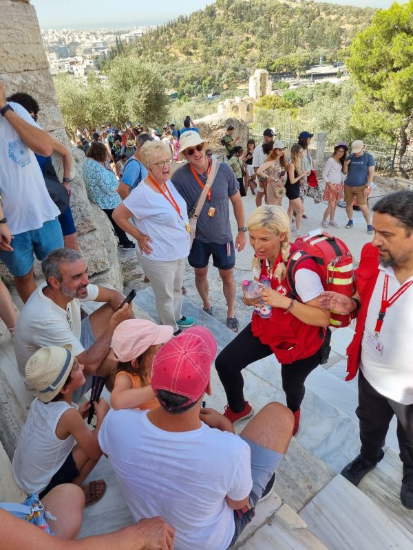 Εθελοντές του Ελληνικού Ερυθρού Σταυρού προσφέρουν βοήθεια σε τουρίστες στην Ακρόπολη.