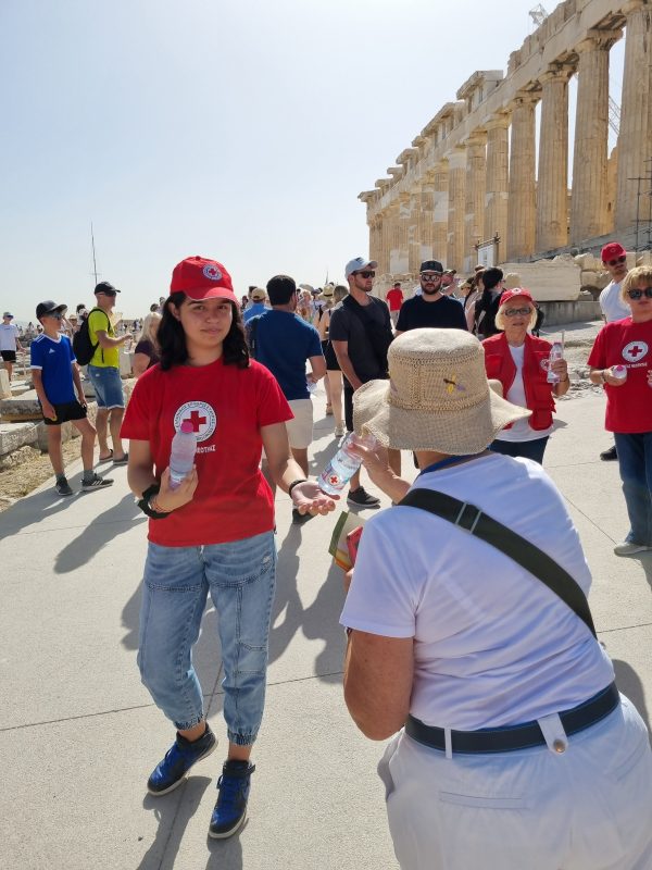 Εθελόντρια του Ελληνικού Ερυθρού Σταυρού προσφέρει νερό σε επισκέπτρια στην Ακρόπολη.