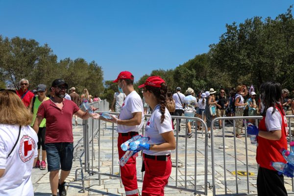 Εθελοντές του Ελληνικού Ερυθρού Σταυρού μοιράζουν νερά σε πολίτες λόγω καύσωνα.