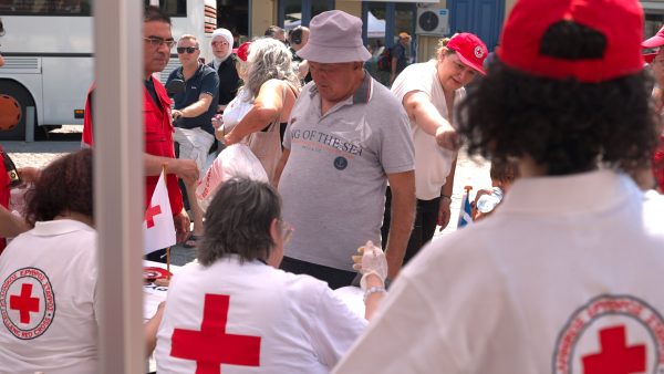 Εθελοντές του Ελληνικού Ερυθρού Σταυρού προσφέρουν βοήθεια σε πολίτες σε εξωτερικό χώρο.