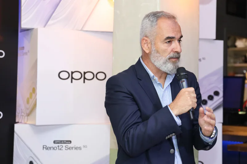 Άνδρας με κοστούμι μιλάει σε μικρόφωνο σε εκδήλωση της OPPO.