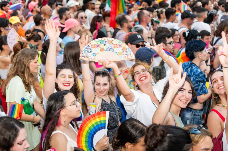 Πλήθος κόσμου γιορτάζει στην παρέλαση του EuroPride 2024 με σημαίες και βεντάλιες στα χρώματα του ουράνιου τόξου.