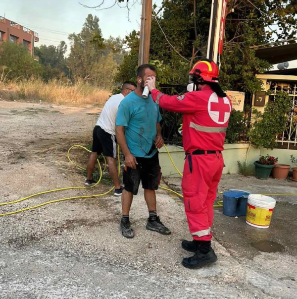Εθελοντής του Ελληνικού Ερυθρού Σταυρού παρέχει πρώτες βοήθειες σε άνδρα.