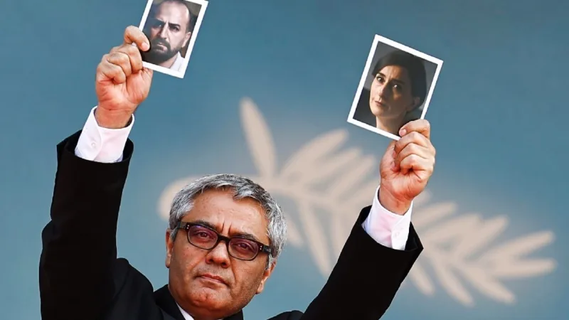 Ο Μοχάμαντ Ρασούλοφ κρατά φωτογραφίες δύο ηθοποιών.
