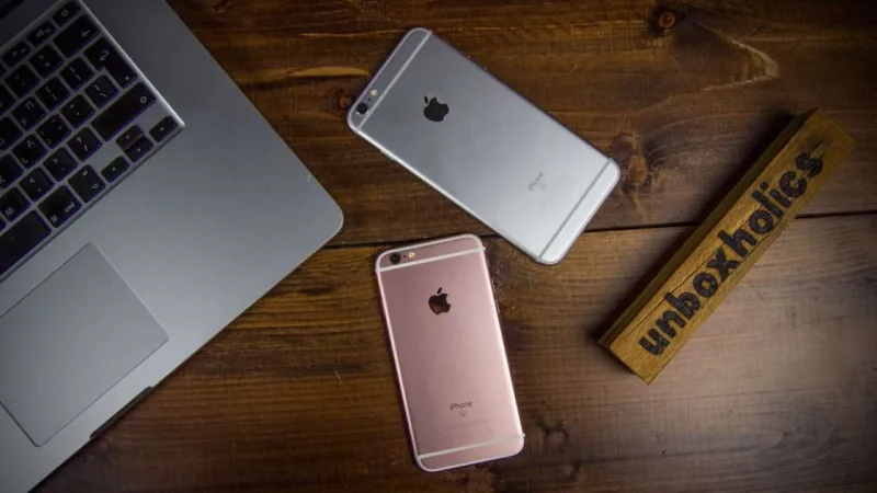 Δύο iPhone και ένας φορητός υπολογιστής πάνω σε ξύλινο γραφείο.