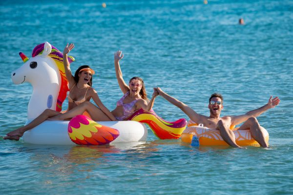 Τρεις φίλοι διασκεδάζουν στη θάλασσα με φουσκωτά παιχνίδια.