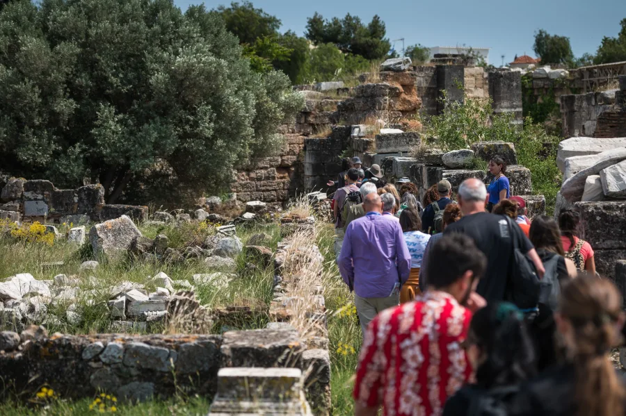Ομάδα ανθρώπων σε ξενάγηση στον αρχαιολογικό χώρο της Ελευσίνας.