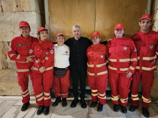 Εθελοντές του Ελληνικού Ερυθρού Σταυρού με άνδρα στα μαύρα.