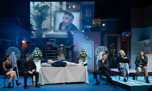 Σκηνή από το μιούζικαλ Μα-Μπαμπά με τους ηθοποιούς σε θεατρικό σκηνικό.