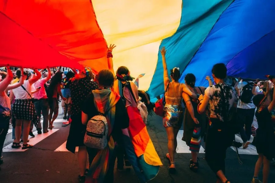 Πλήθος κόσμου κρατά μια τεράστια σημαία του Pride σε δρόμο της Αθήνας.