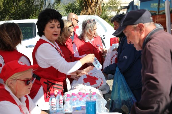 Εθελοντές του Ελληνικού Ερυθρού Σταυρού μοιράζουν νερό και είδη πρώτης ανάγκης σε πολίτες.