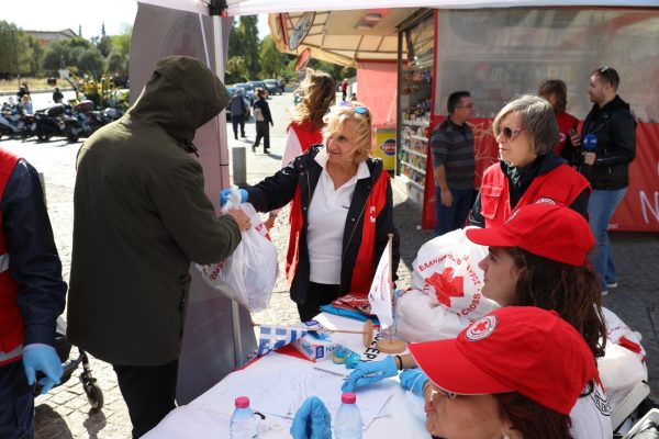 Εθελοντές του Ελληνικού Ερυθρού Σταυρού μοιράζουν ανθρωπιστική βοήθεια σε άστεγο στο κέντρο της Αθήνας.