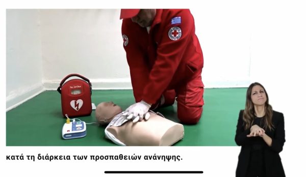 Εθελοντής του Ελληνικού Ερυθρού Σταυρού κάνει ΚΑΡΠΑ σε πρόπλασμα με διερμηνεία στη νοηματική.