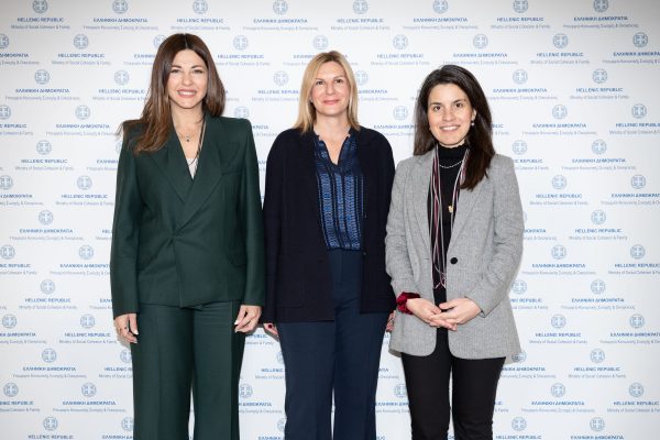 Τρεις γυναίκες ποζάρουν μπροστά από φόντο με το εθνόσημο και την επιγραφή Ελληνική Δημοκρατία.