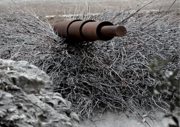 Εικαστική εγκατάσταση με σκουριασμένο μεταλλικό σωλήνα μέσα σε ξερά κλαδιά.