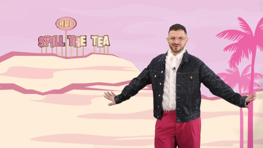 Παρουσιαστής σε στούντιο με φόντο 'Spill The Tea' και φοίνικες.