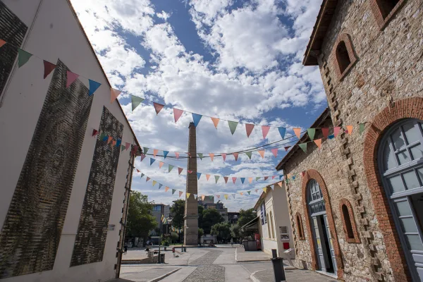 Άποψη της Τεχνόπολης Δήμου Αθηναίων με πολύχρωμα σημαιάκια και την καμινάδα στο βάθος.
