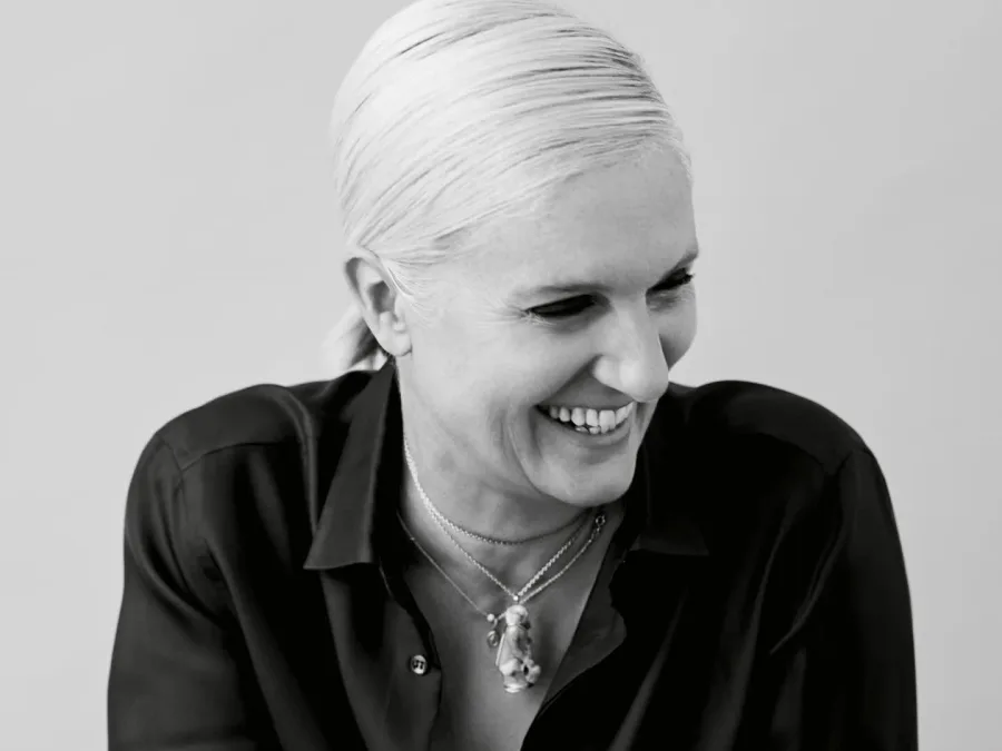 Ασπρόμαυρο πορτρέτο της Maria Grazia Chiuri να χαμογελά.