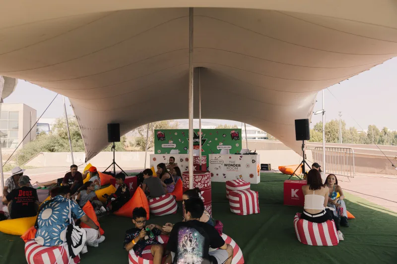 Κόσμος χαλαρώνει σε πουφ κάτω από τέντα στο Mad VMA Village Festival.