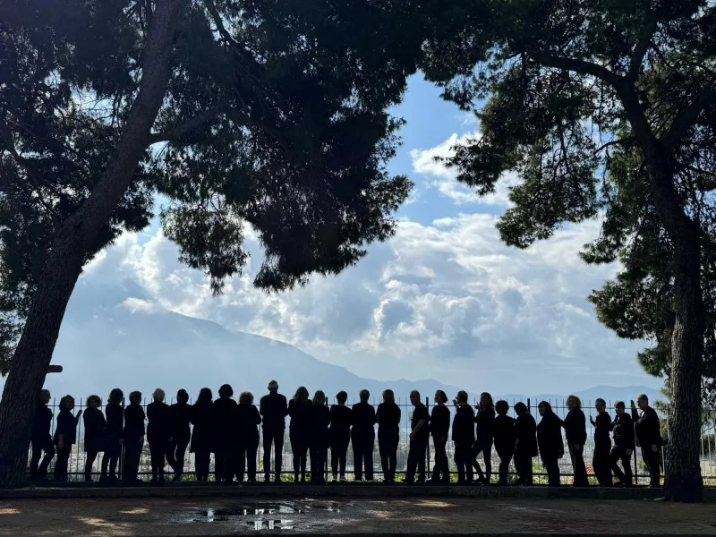 Ομάδα ανθρώπων σε σιλουέτα μπροστά από ορεινό τοπίο στην Καλαμάτα.