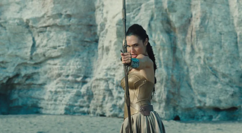 Η Wonder Woman σημαδεύει με το τόξο της μπροστά από έναν βράχο.