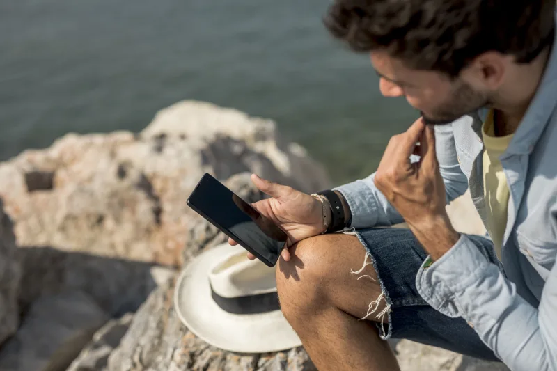 Κοντινό πλάνο σε οθόνη smartphone με εφαρμογές για την οργάνωση καλοκαιρινού ταξιδιού.