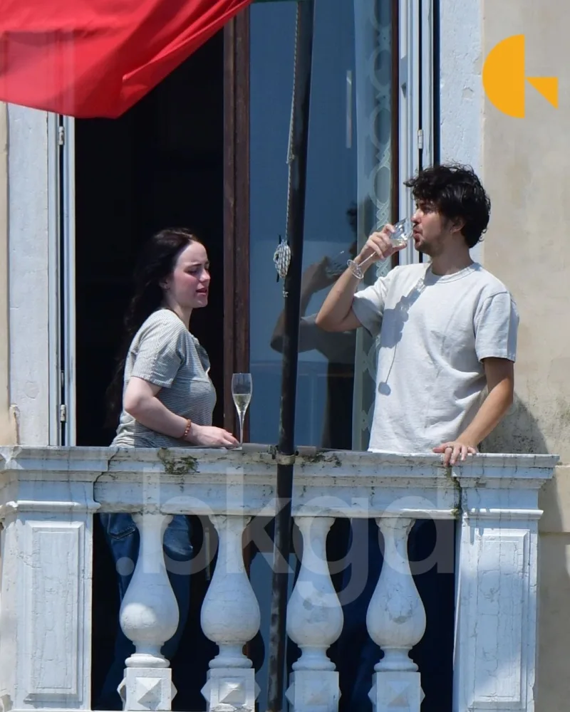 Η Billie Eilish και ο Nat Wolff ανταλλάσσουν ένα φιλί σε μπαλκόνι στη Βενετία.