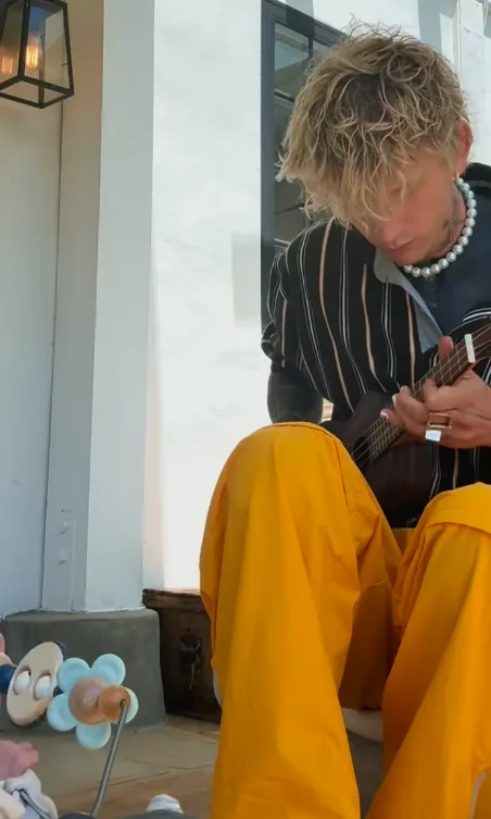 Ο Machine Gun Kelly παίζει γιουκαλίλι μπροστά σε ένα μωρό.