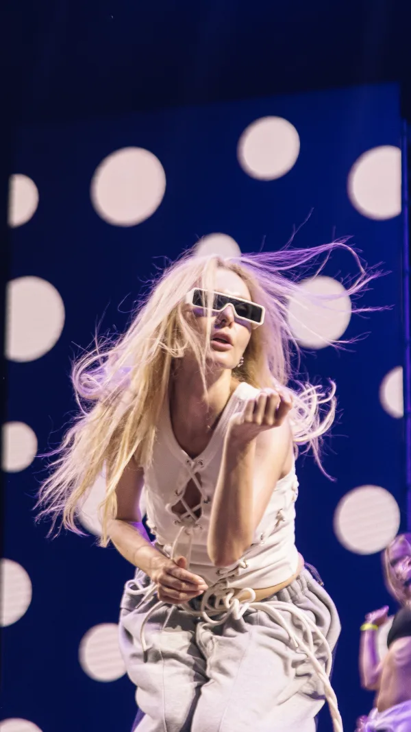 Η performer με τα λευκά γυαλιά και τα μακριά μαλλιά στη σκηνή των Mad VMA 2025 από τη ΔΕΗ.