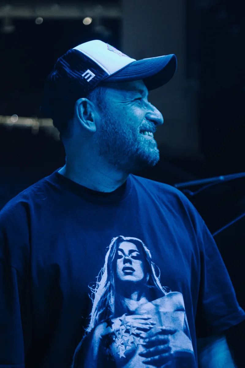 Ο παρουσιαστής του Mad VMA 2025 από τη ΔΕΗ φοράει καπέλο και μπλούζα με στάμπα, προετοιμάζοντας τη μεγαλύτερη μουσική γιορτή.