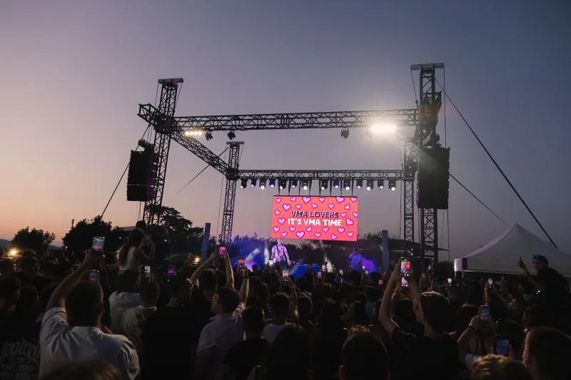 Καλλιτέχνης στη σκηνή του Mad VMA Village Festival μπροστά σε πλήθος.